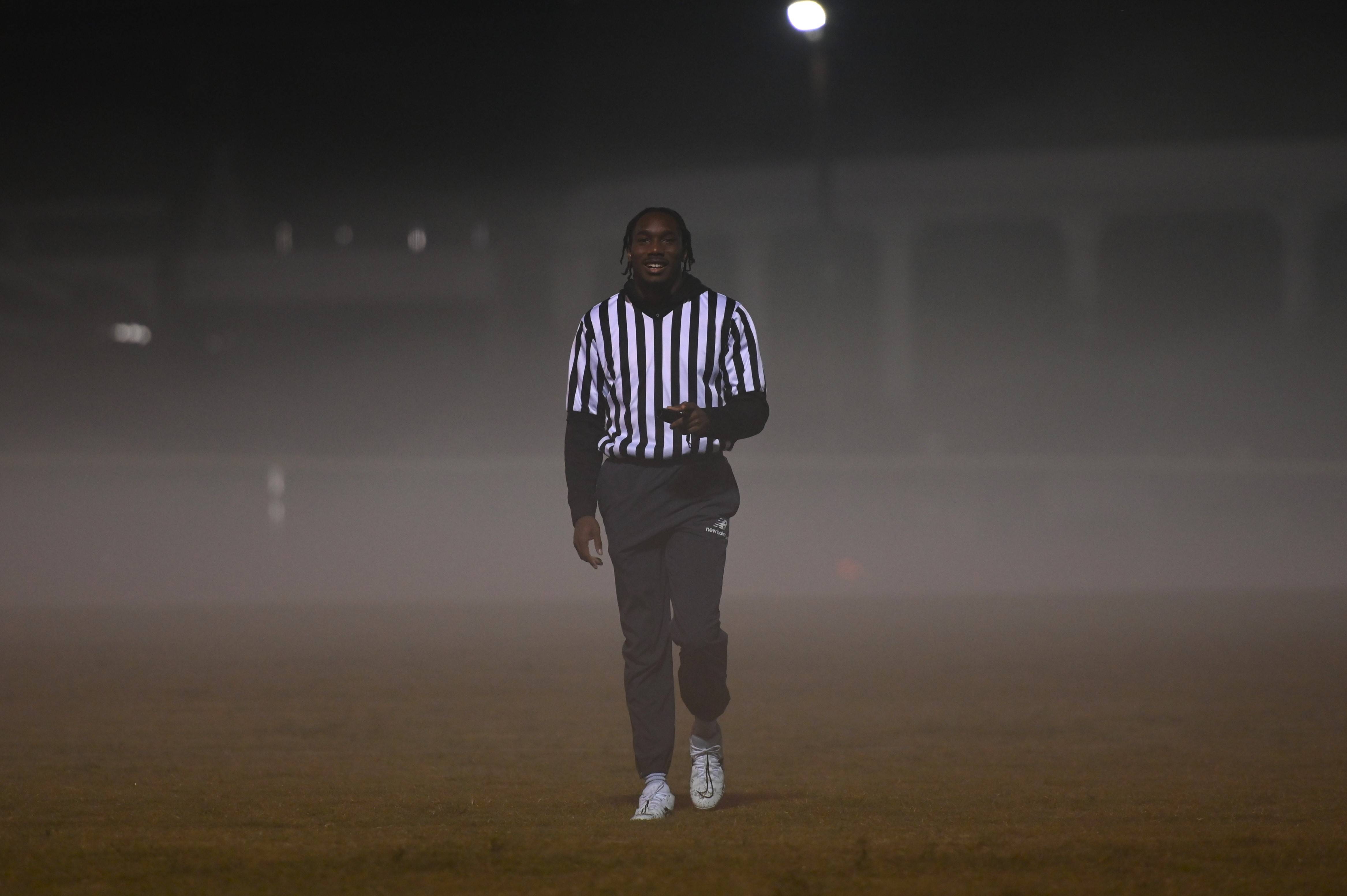 Man reffing flag football on a foggy night.