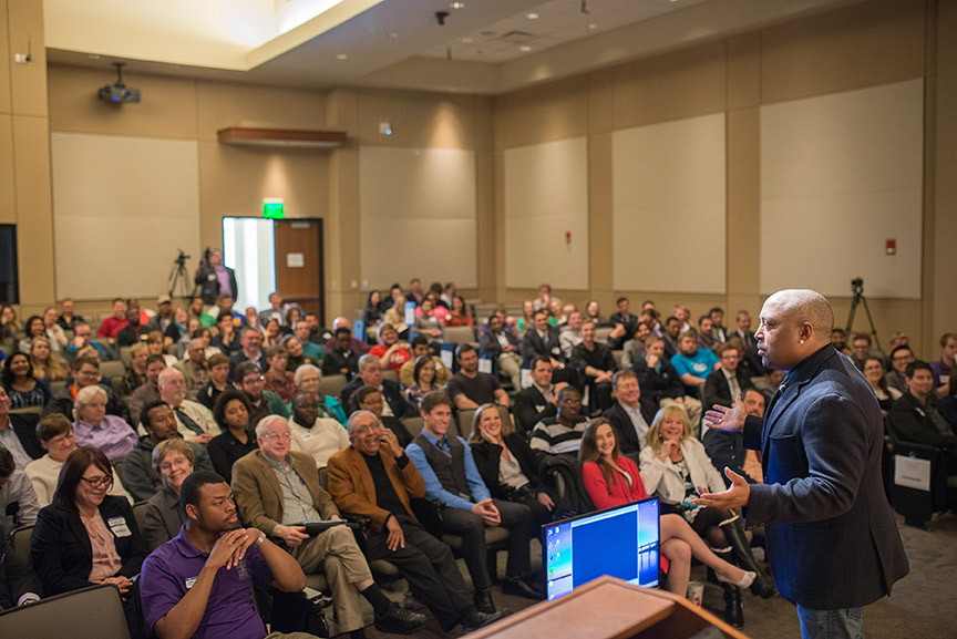 Daymond John speaks to a large audience while standing on stage.