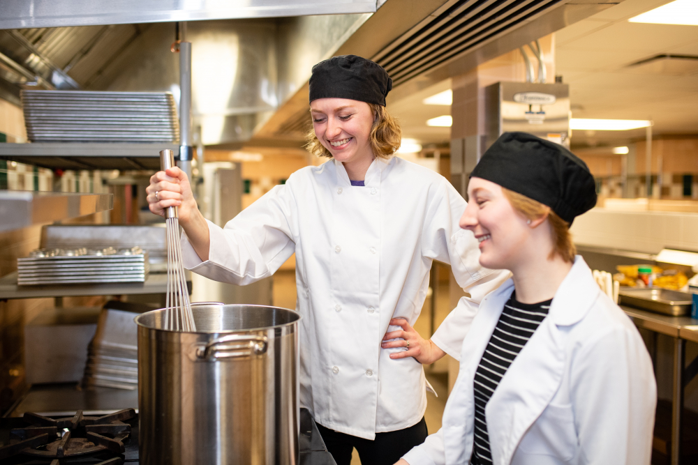 Students stir a pot in a food lab