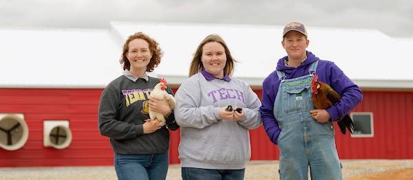 Agriculture students standing in front of the Poultry Center holding chickens.