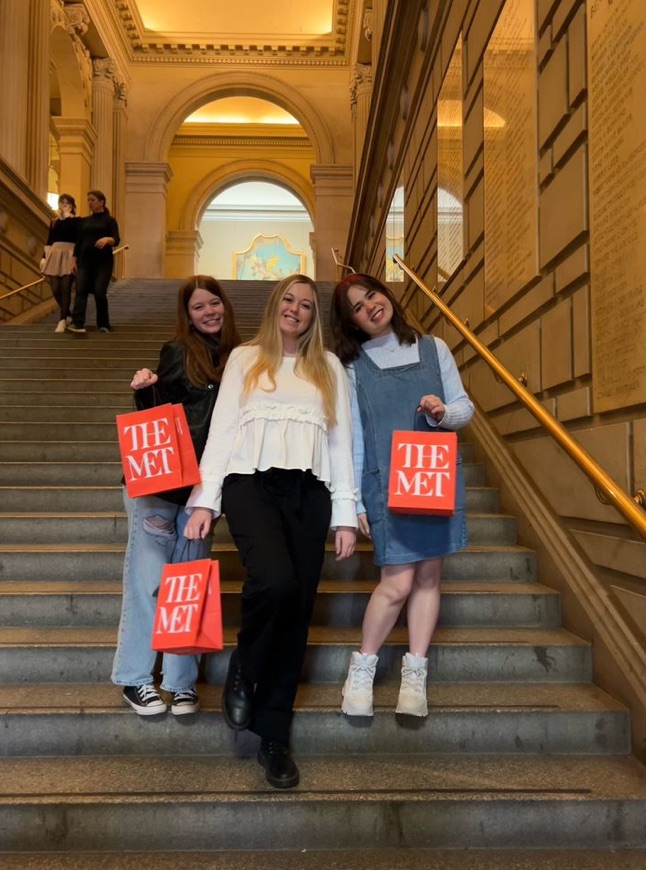 Students showing off their purchases from The Met on the iconic interior staircase