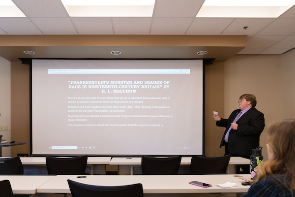 Student standing at the front of the classroom giving a presentation on Frankenstein