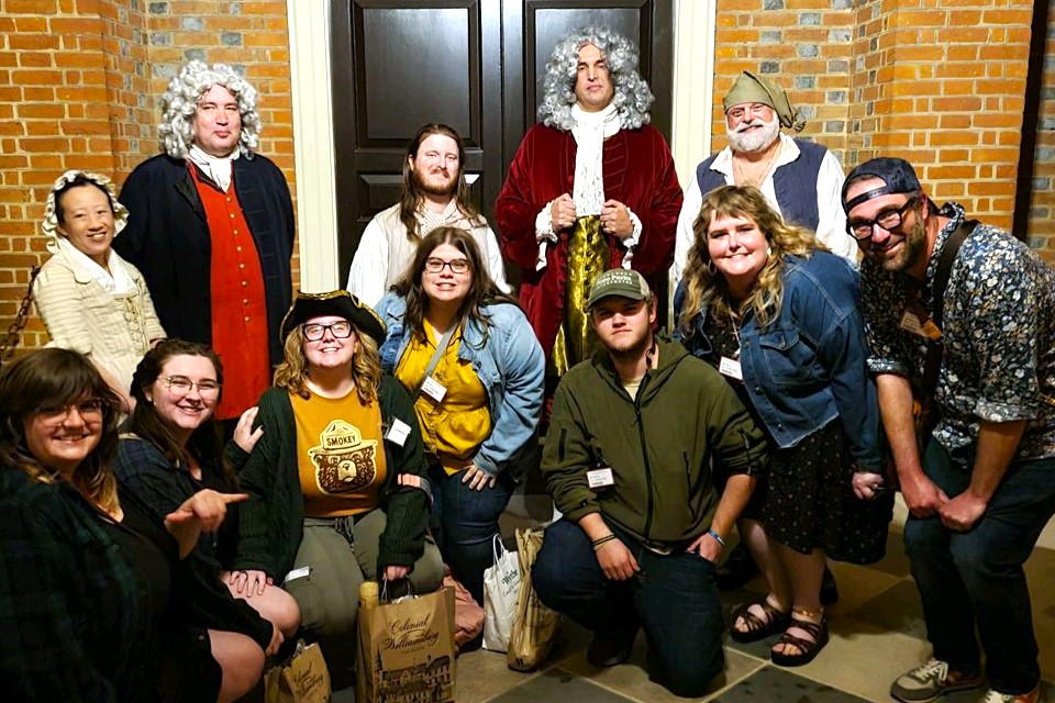 History students & faculty standing with Colonial Williamsburg staff in historical costumes.