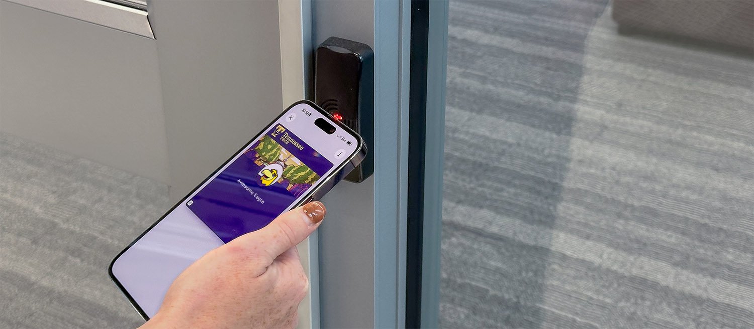 A individual holding an iPhone with the wallet app open using the TN Tech digital ID to open a door lock.