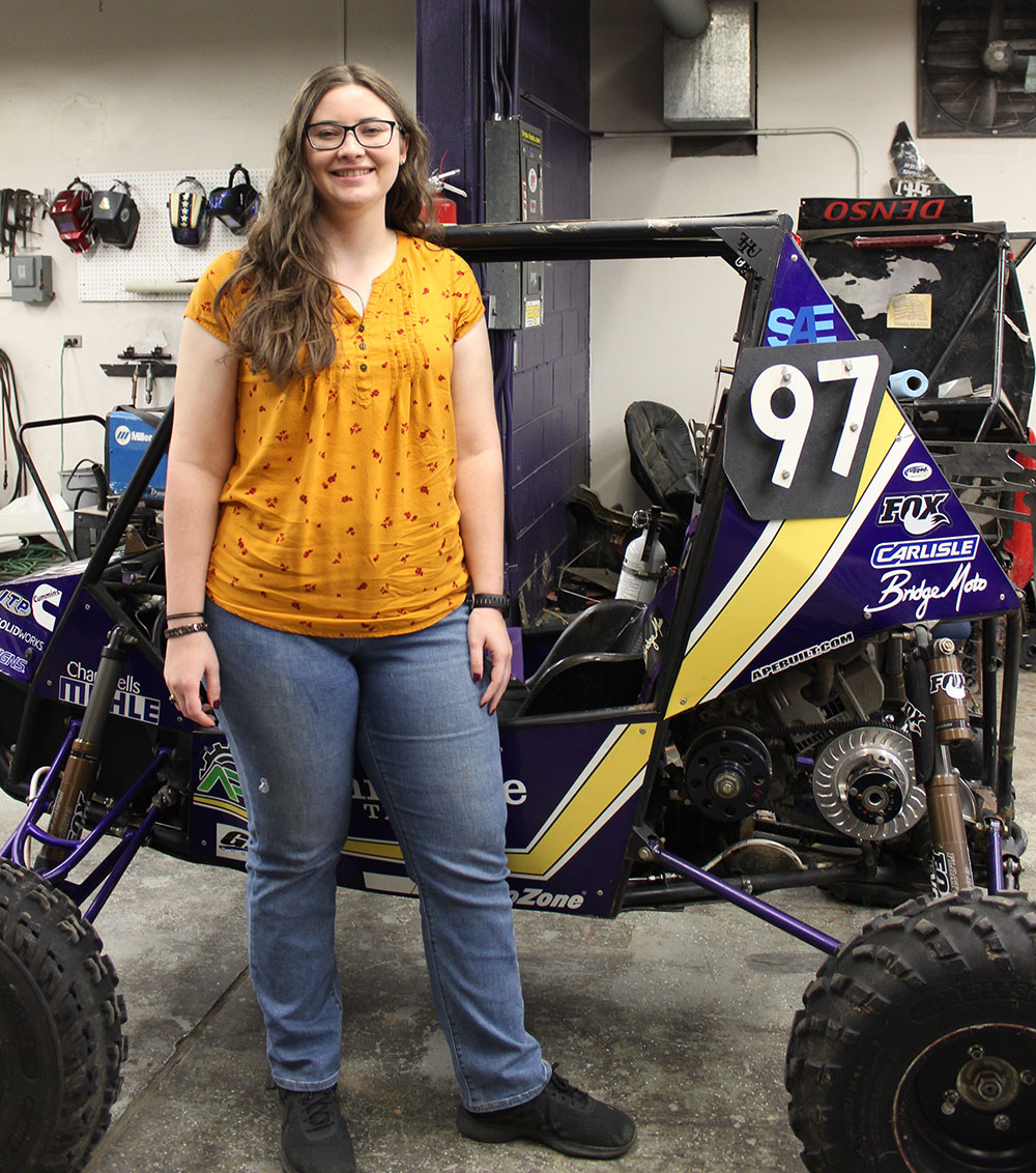 Student standing with Baja car