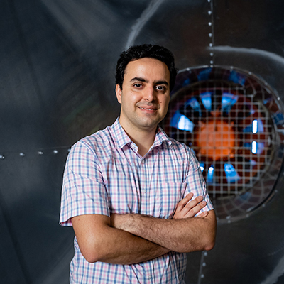 Ahmad Vaselbehagh standing infront of the wind tunnel in the fluid dynamics lab