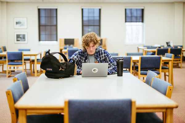 A student at a table with a laptop in the library.