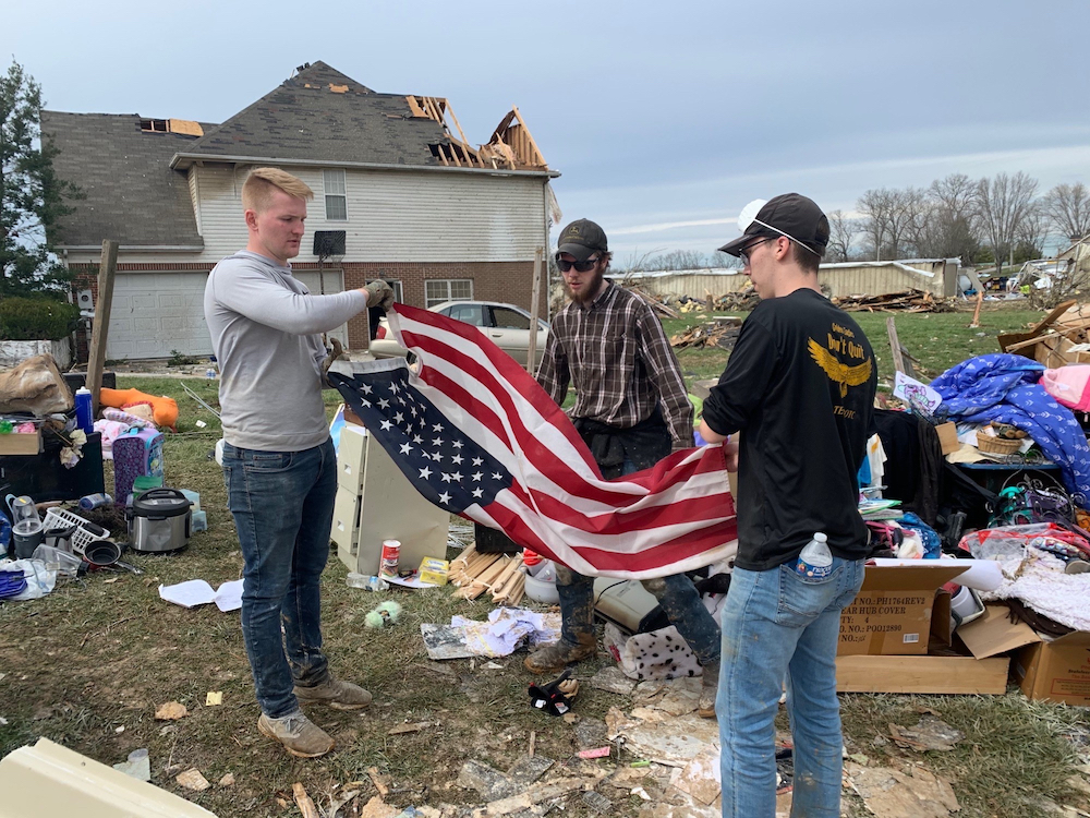 Tennessee Tech ROTC cadets Josh Walkup (in gray shirt) and Jacob Nelson (in black cap) help a volunteer fold up a flag found at Mike Phillips’ house on Herald Court.