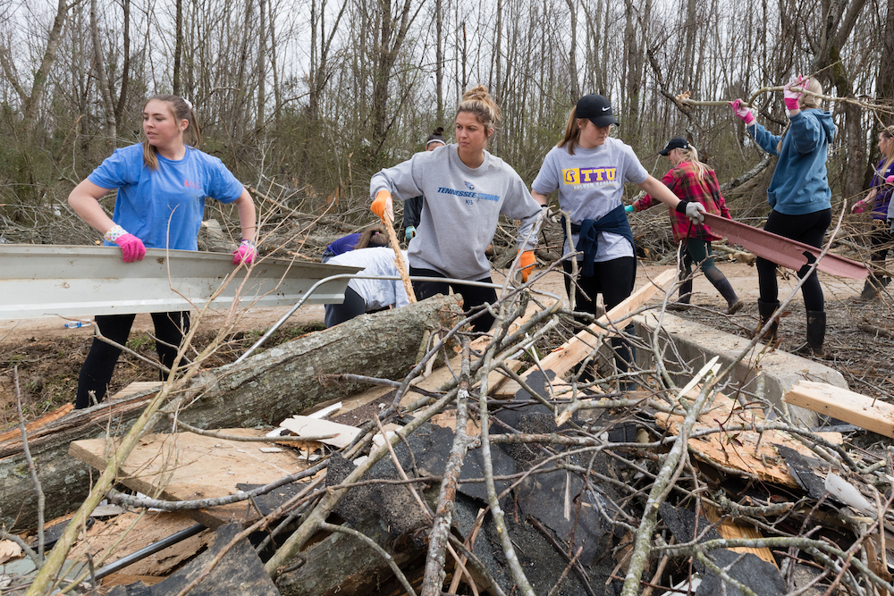 Members of Tennessee Tech’s softball team help with clean-up efforts on Wednesday in a neighborhood close to campus that was devastated by on F-4 tornado on Tuesday.
