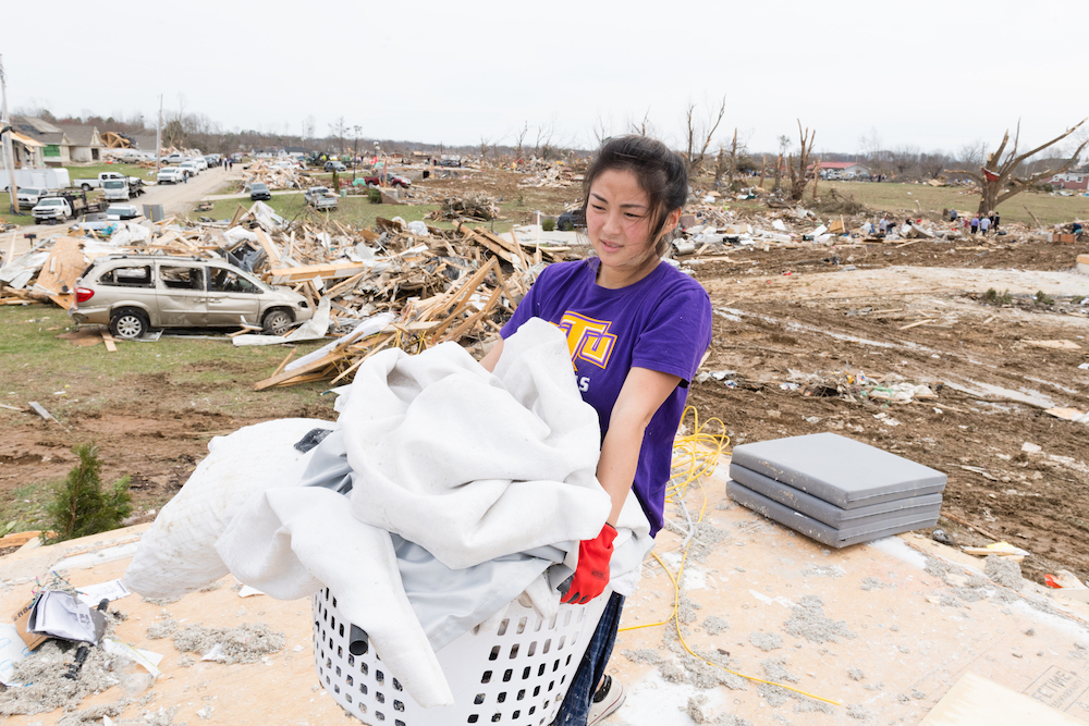 Tennessee Tech student Lindsey Ngo helps move debris on Wednesday at a neighborhood devastated by an F-4 tornado just a few miles from campus.