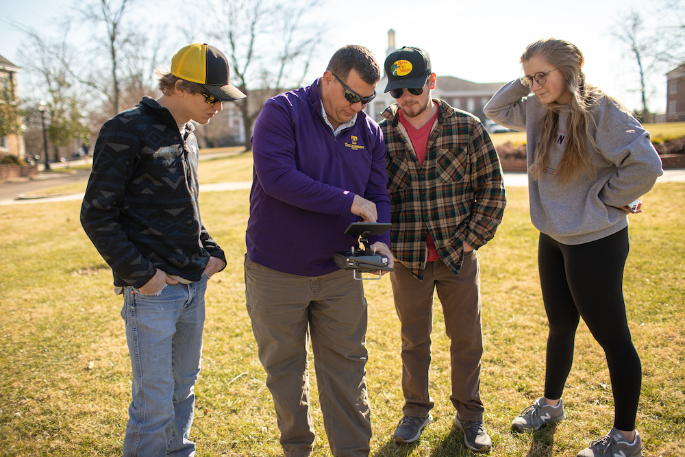 Michael Nattrass, assistant professor of agronomy and soils in the School of Agriculture, explains the controls of a drone to students in his class.