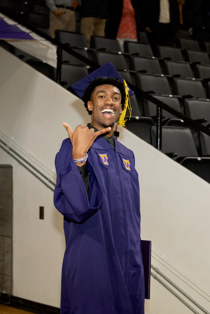 A student goes a wings up gesture at commencement.