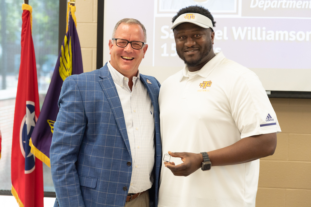 Sammuel T. Williamson, Assistant Football Coach, receives a 15-year service pin from Director of Athletics Mark Wilson, left.