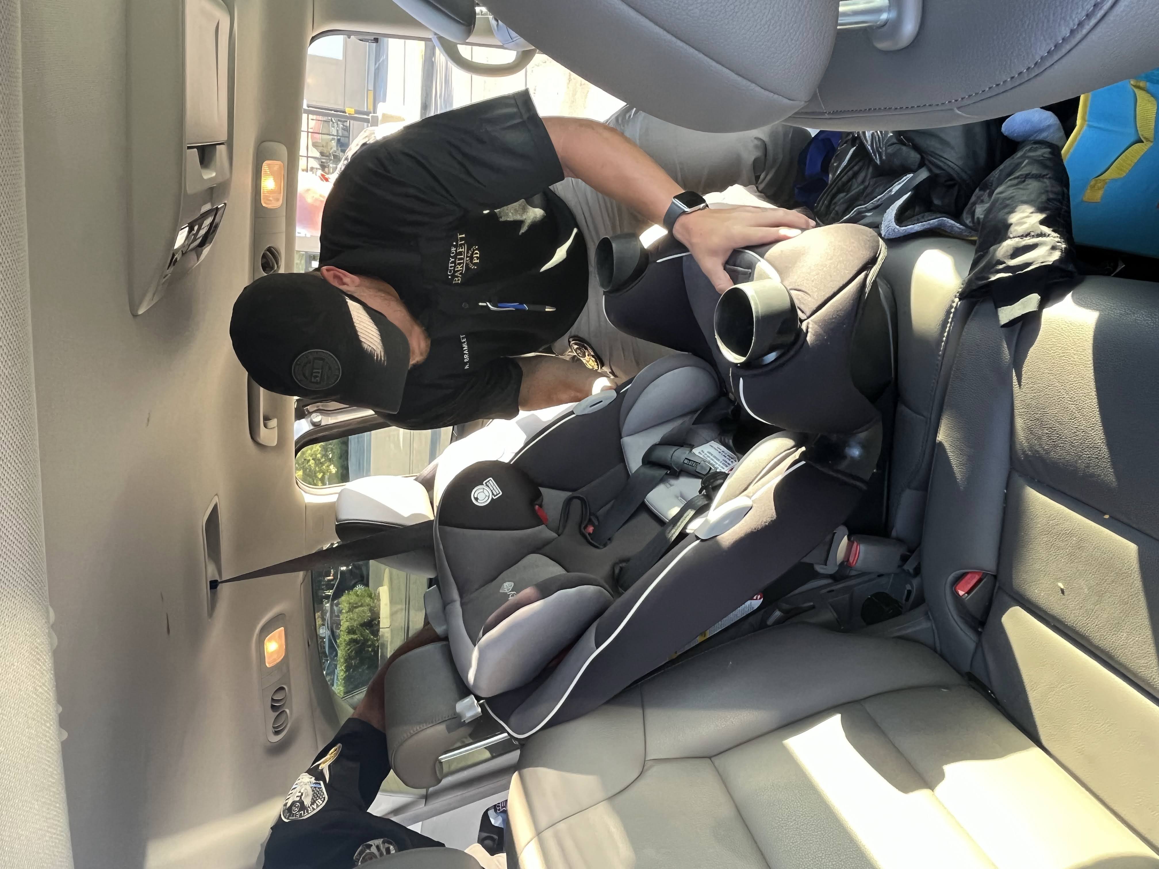 Officer Nick Bramlett from the Bartlett, Tennessee police department checks the installation of a child car seat.