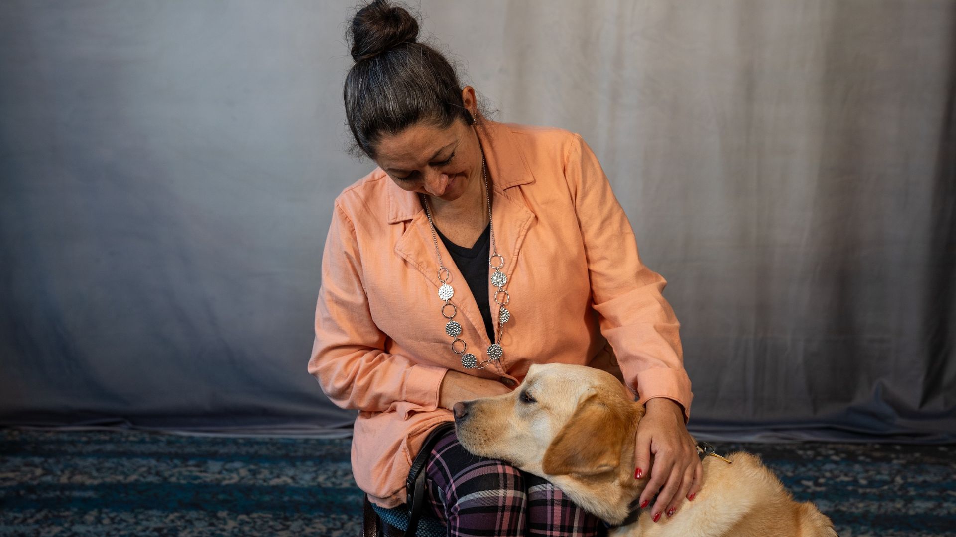 Amanda Juetten is seated smiling with her guide dog, Colonel