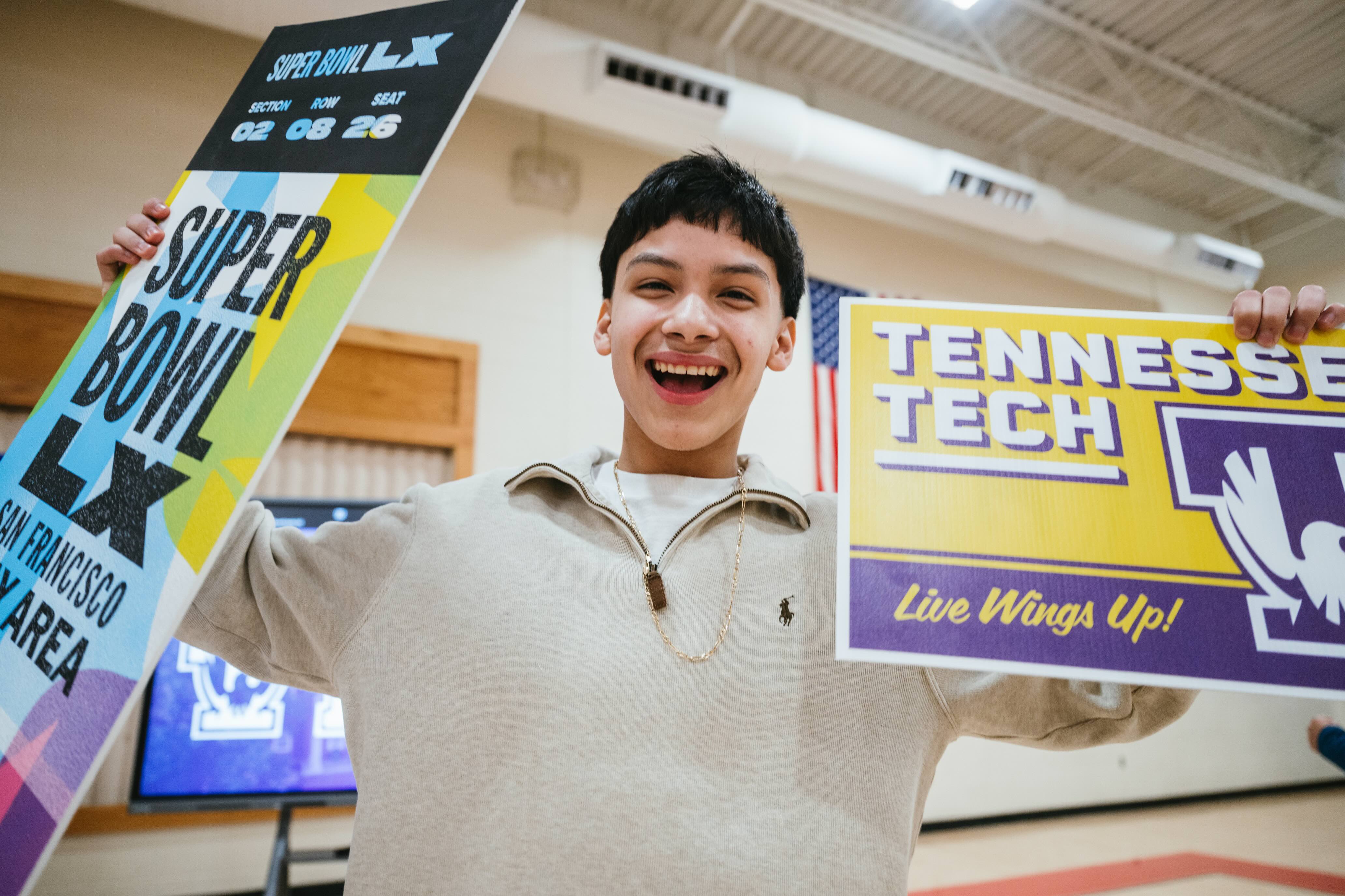 Eduardo Mendez smiles as he holds up a Super Bowl LX sign and a Tennessee Tech sign.