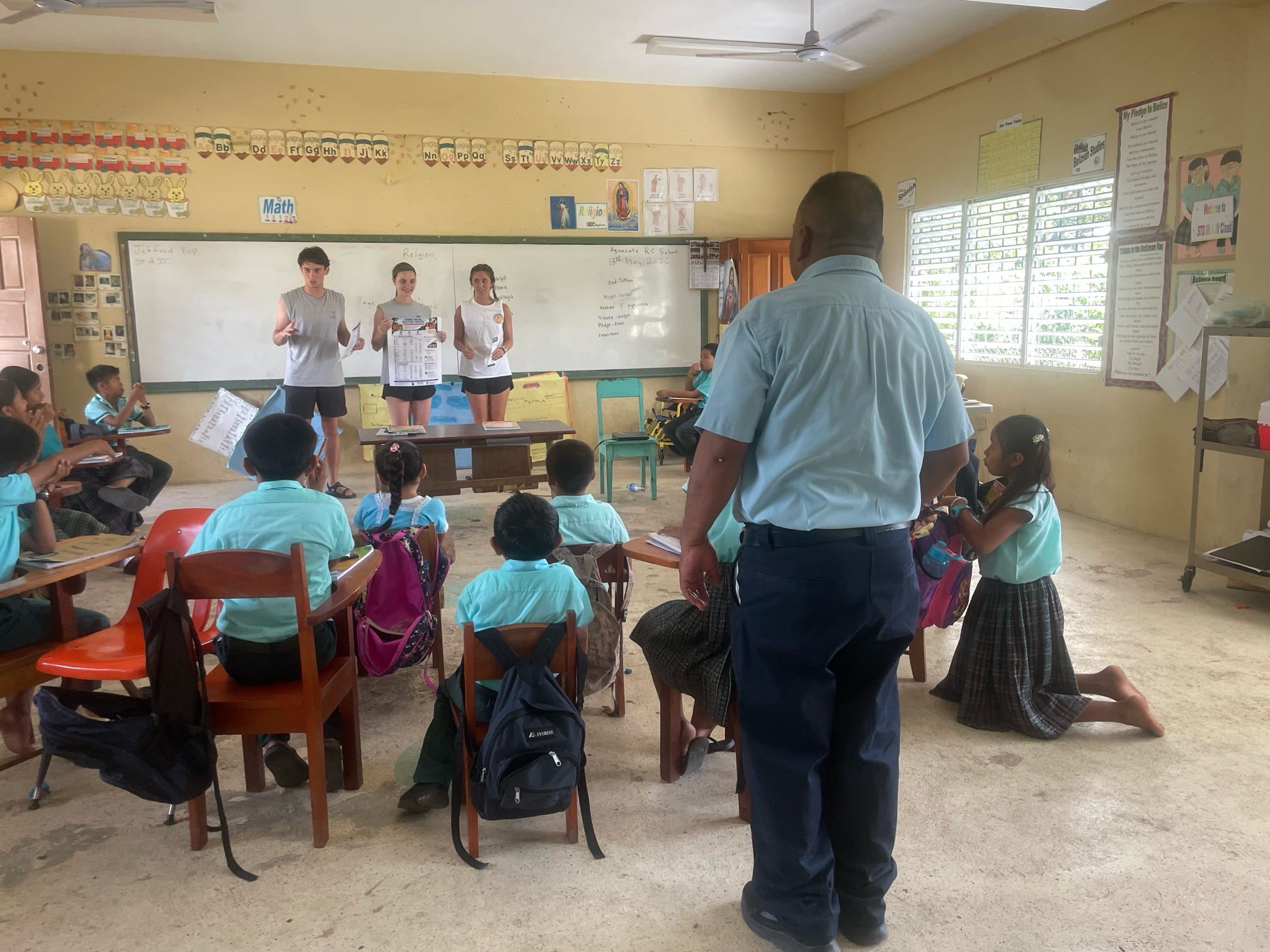 Three Tech students stand at the front of a classroom as young students look on. 