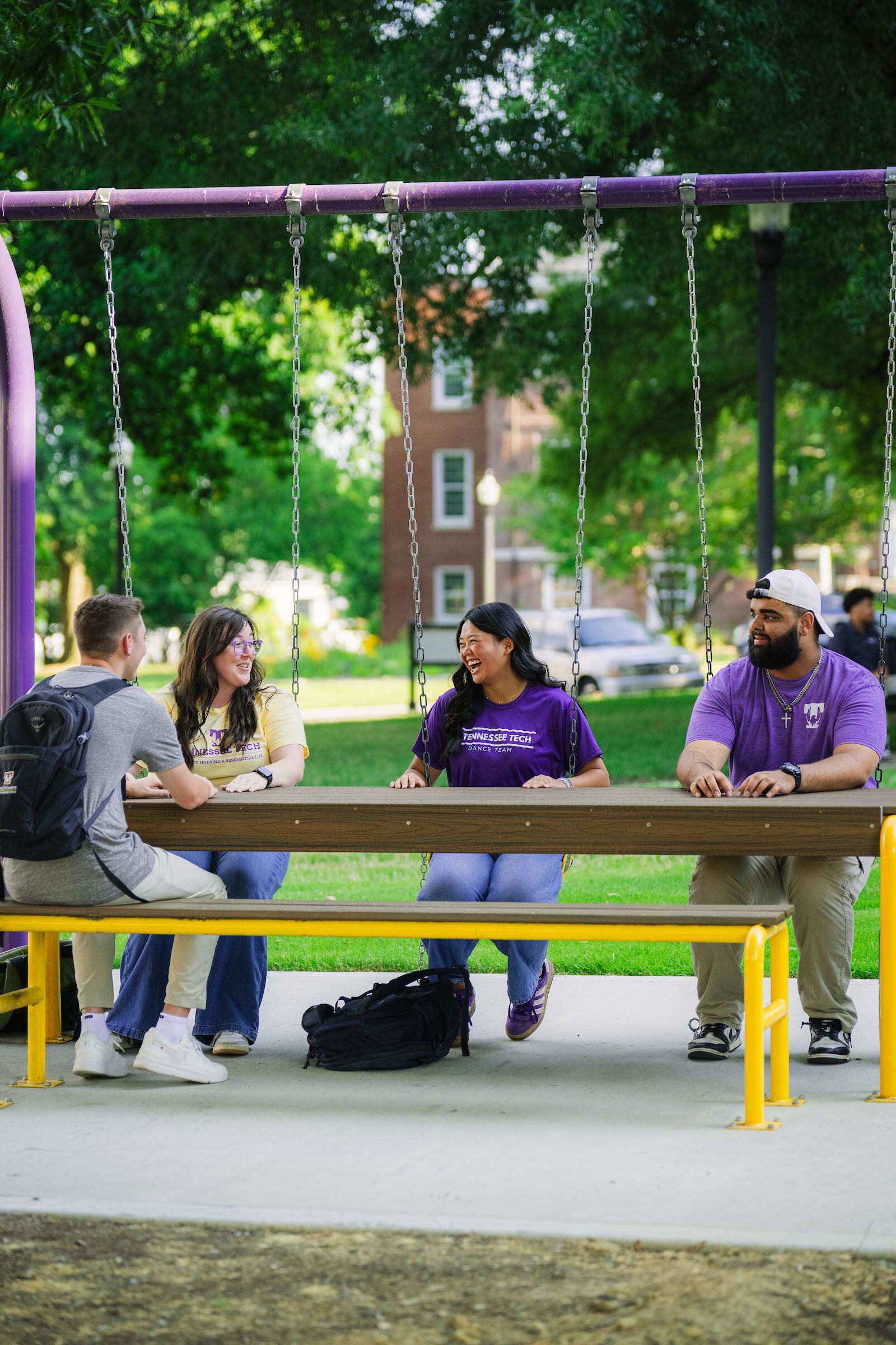 Four students smile as they sit at a picnic table area outside Derryberry Hall. 