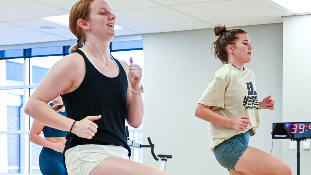 Two female students exercising in a group fitness class. 