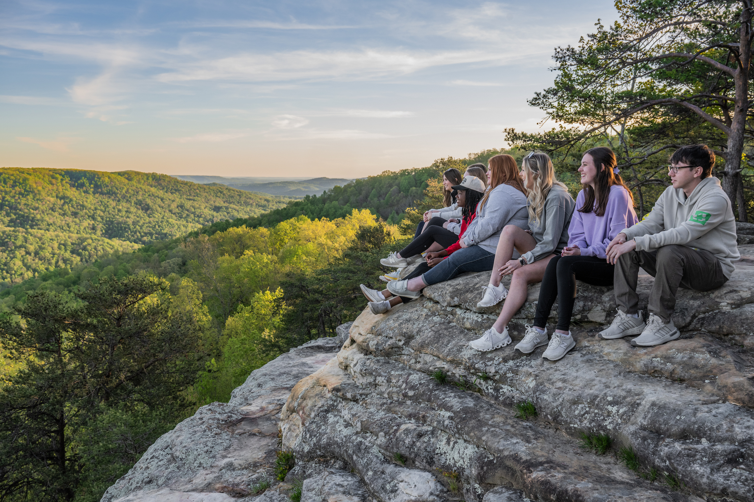 Students on top of Bee Rock with a view of the Tennessee hills behind them at sunset