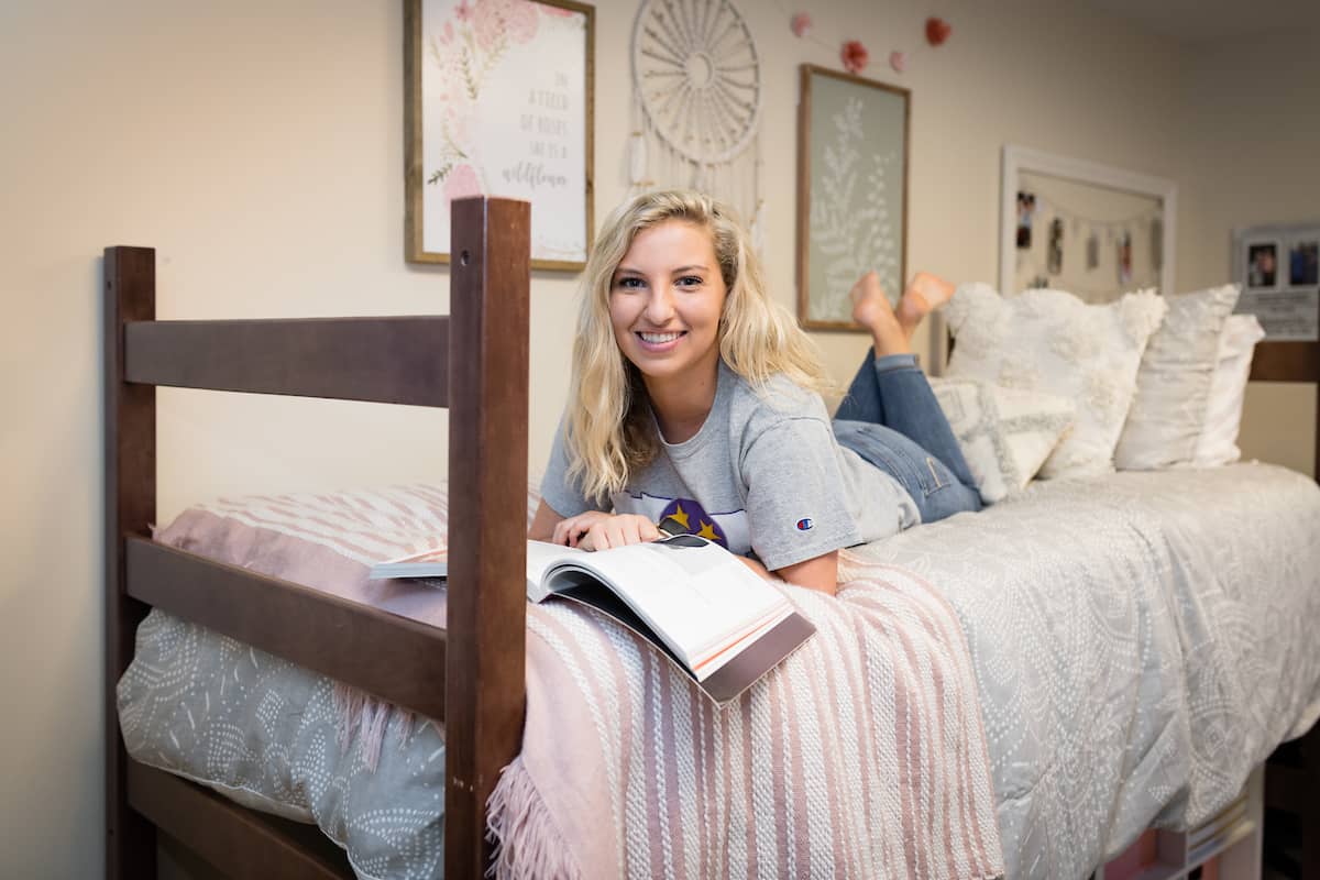 Student sitting on a bed and studying.