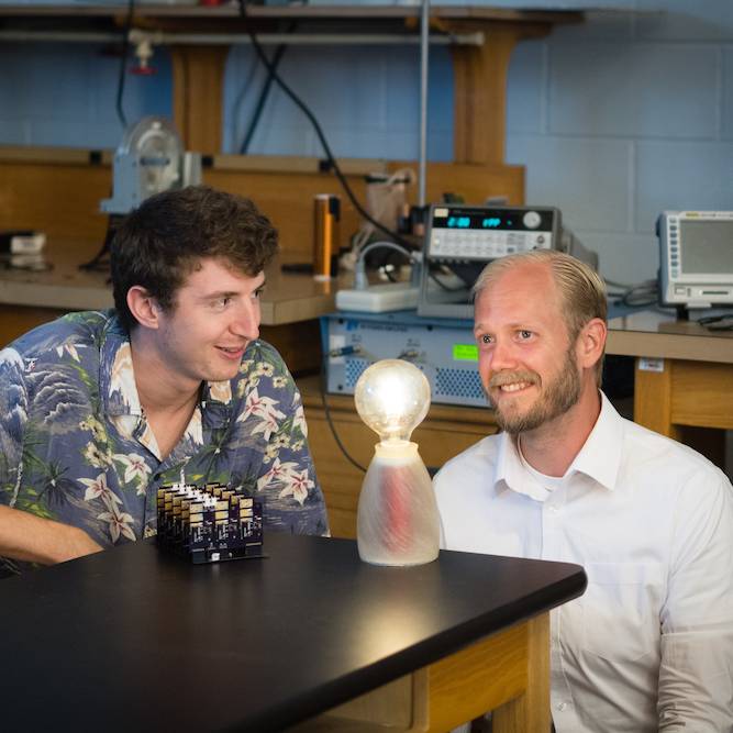 Electrical engineering master’s student Tanner Mingen, left, looks at the wireless charging module with Charles Van Neste, research assistant professor with CESR.