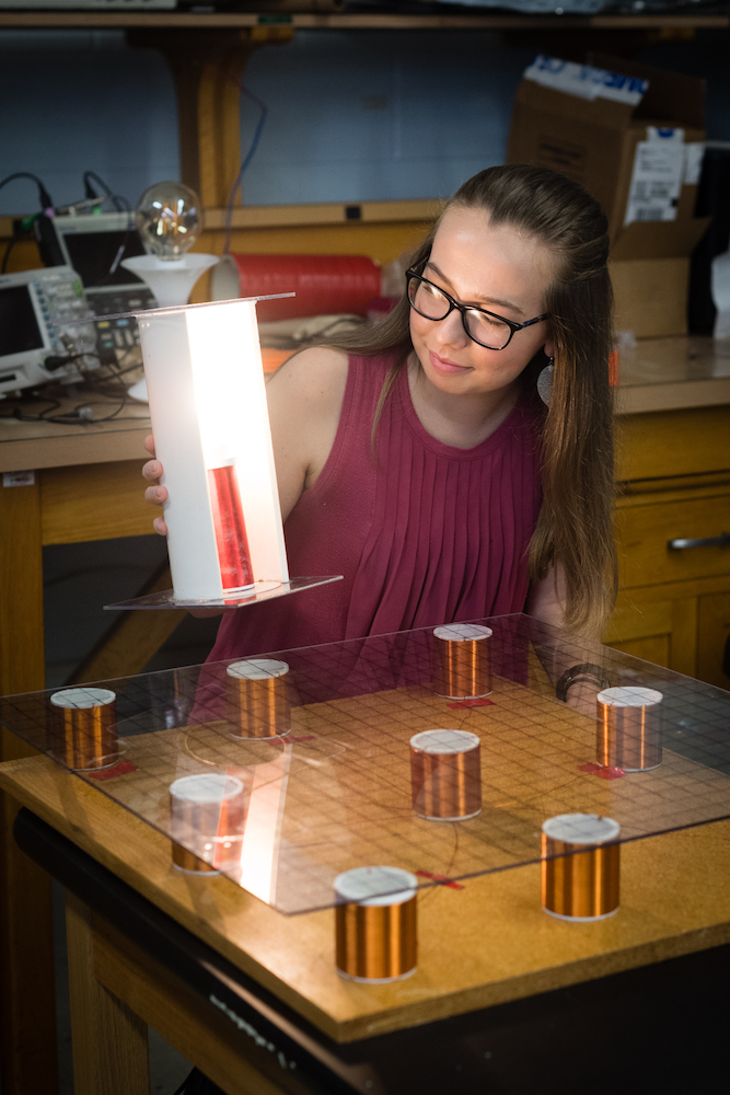 Whitney Kirby, senior electrical engineering student, tests her wireless charging platform with a lamp.