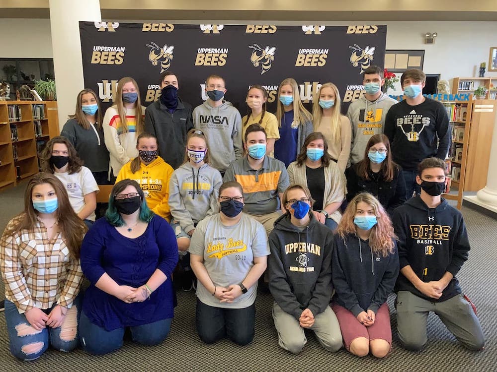 A group of students posing in the library. The students are wearing face masks.