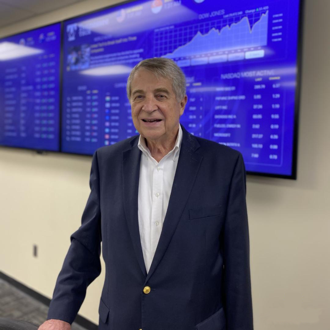 A photo of Buzz Heidtke in front of the monitors in the Heidtke Trading Room