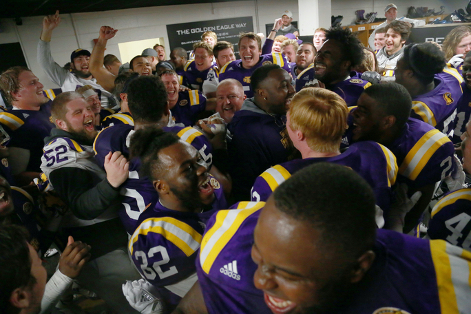 Coach Alexander celebrates with the football team in the locker room.