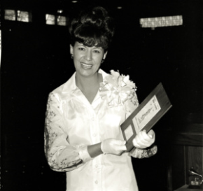 A black and white photo of Dottie West holding a plaque.