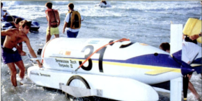 Photo of the Tech Torpedo II in the water with several people carrying it and walking around.