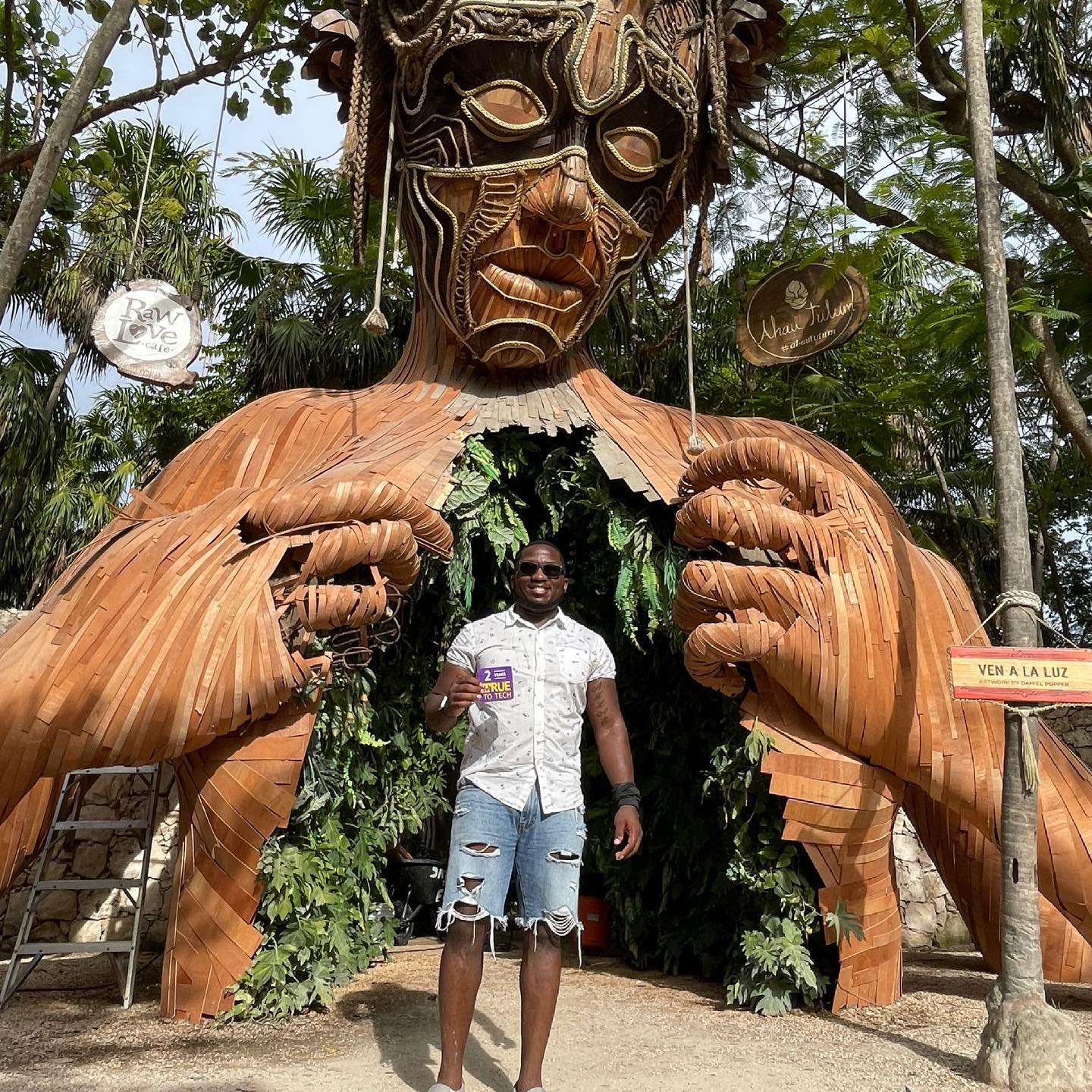 Dontrell Baines holding his True To Tech magnet in front of a sculpture in Tulum, Mexico.