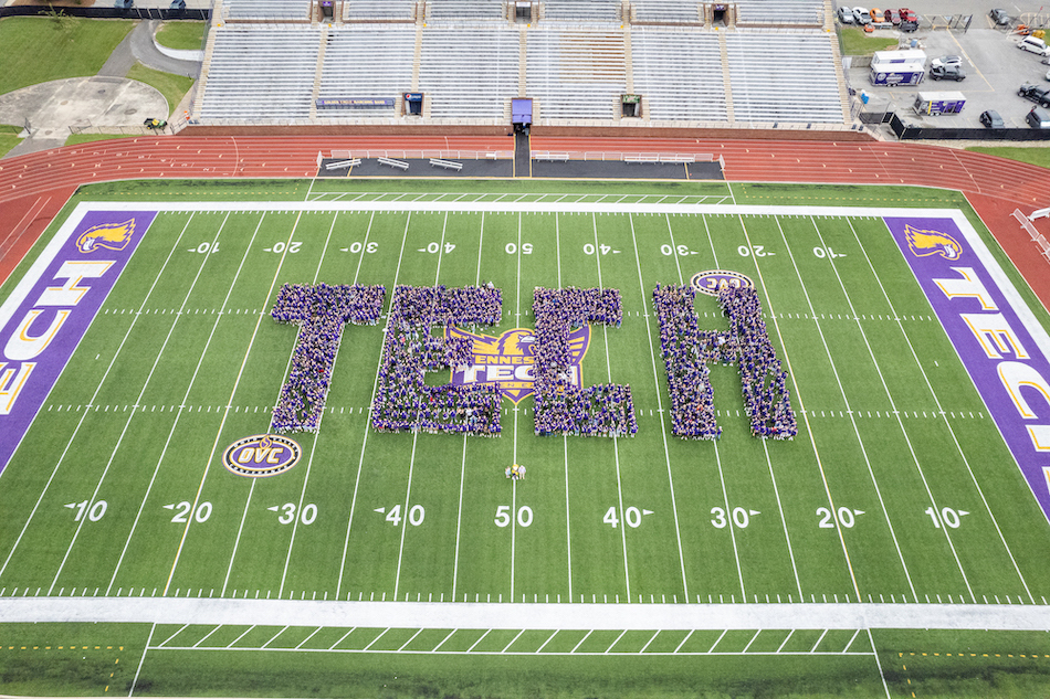 Students arranged on Overall Field in a formation that reads "TECH"