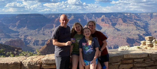 Brent Brown holds a 20 year True To Tech magnet with his wife and two daughters at a Grand Canyon overlook.