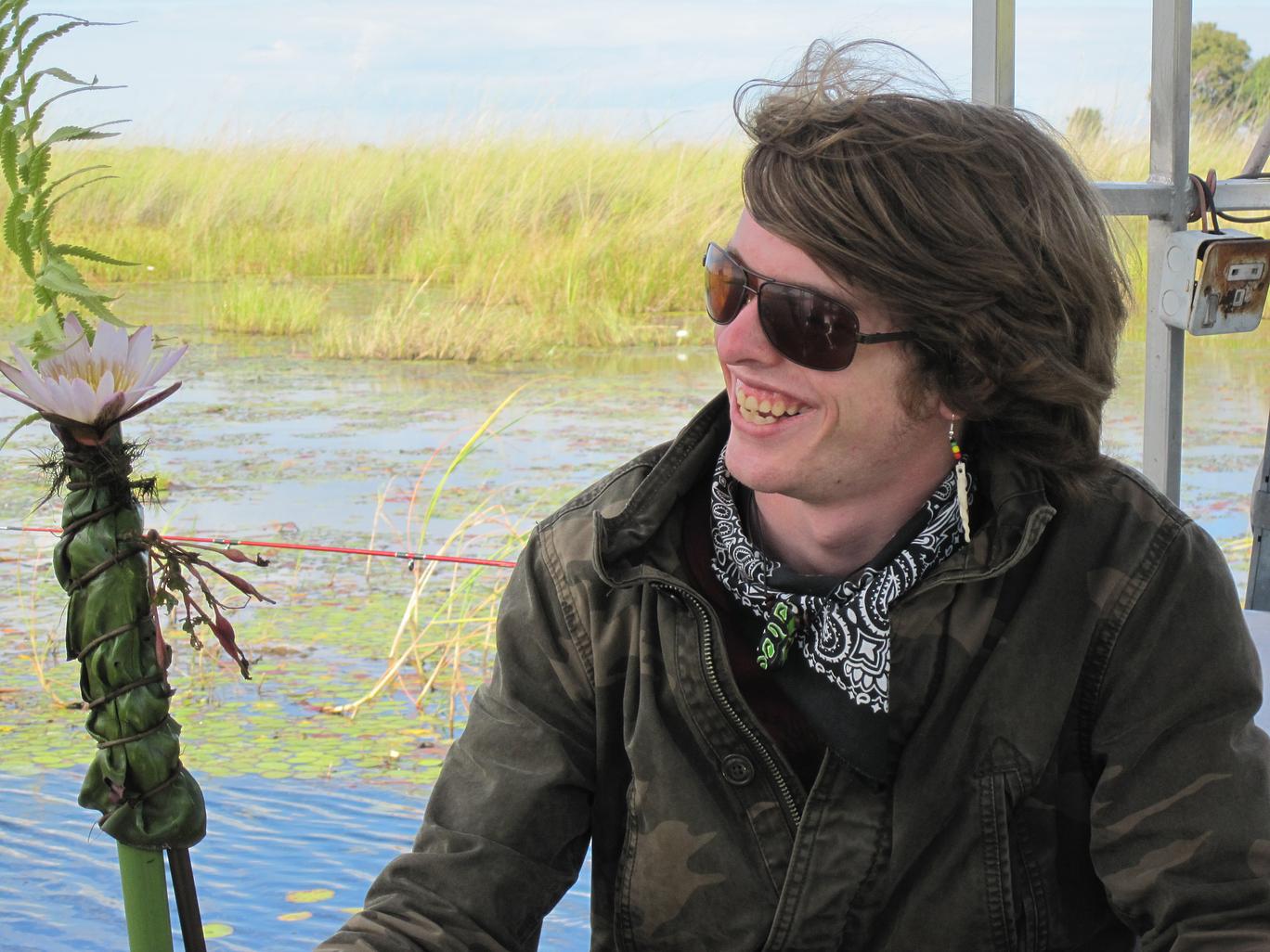 Seth Reichman smiles on an airboat with marsh behind him.
