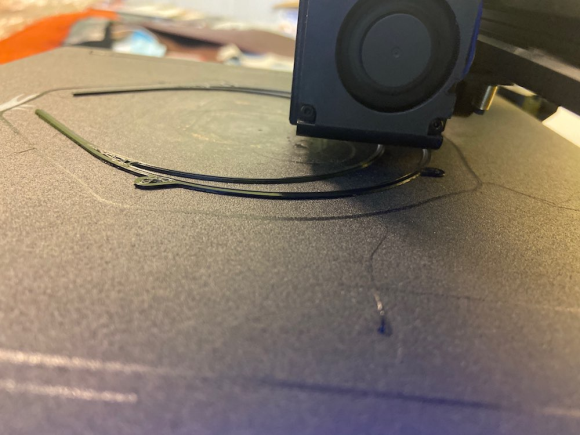 A 3-D printer is printing the outline of the headband portion of a face mask.