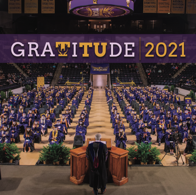 The cover of the Gratitude publication. It is a photo of graduation in Hooper Eblen Center. We see President Oldham from the back in his regalia standing before socially distanced graduates in purple robes and face masks. The title reads "Gratitude 2021."