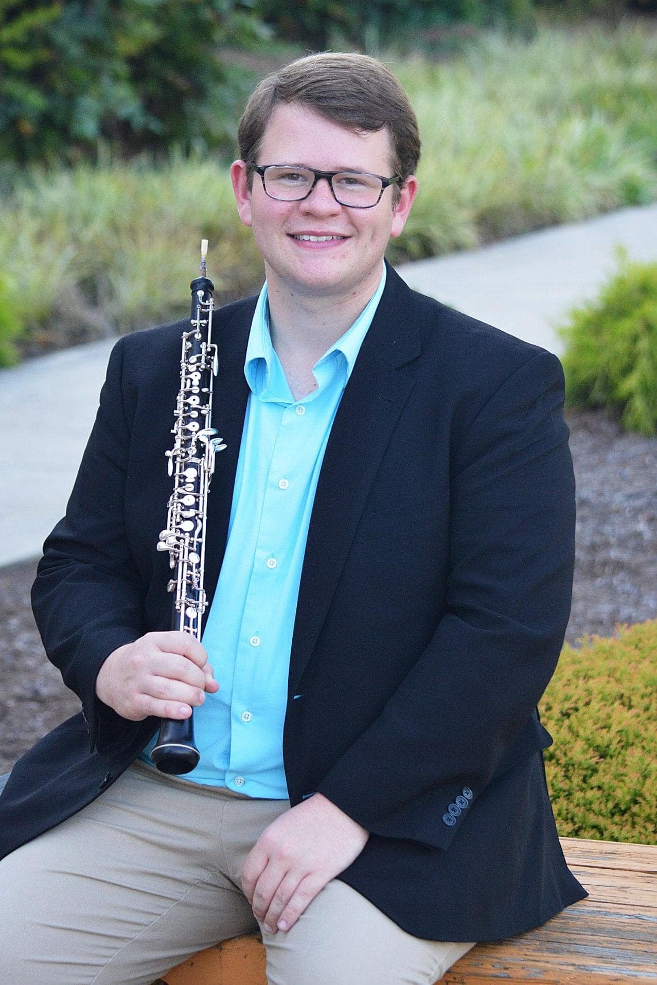 Hunter Collins sits holding an oboe.