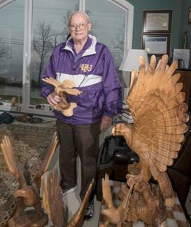 Charlie standing with carved wooden eagles.