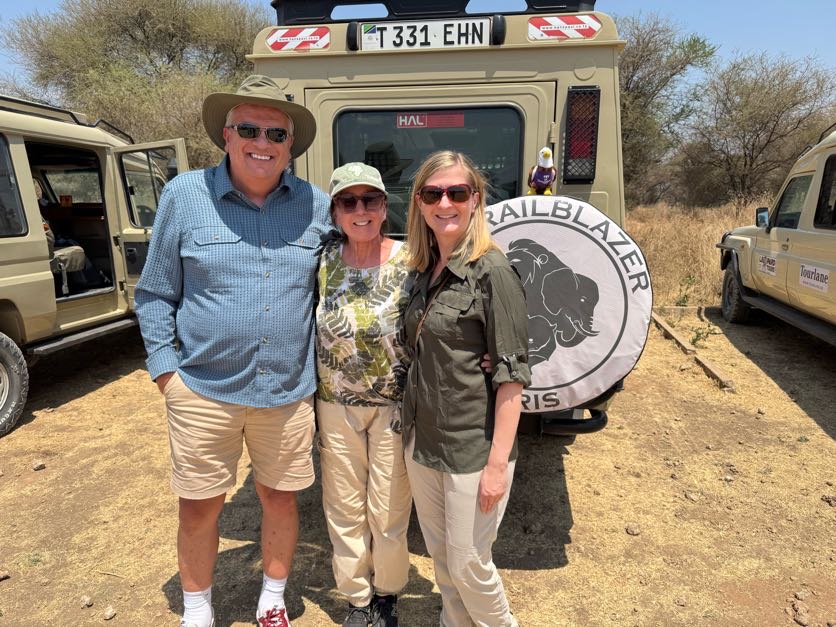 three people standing outside safari jeep