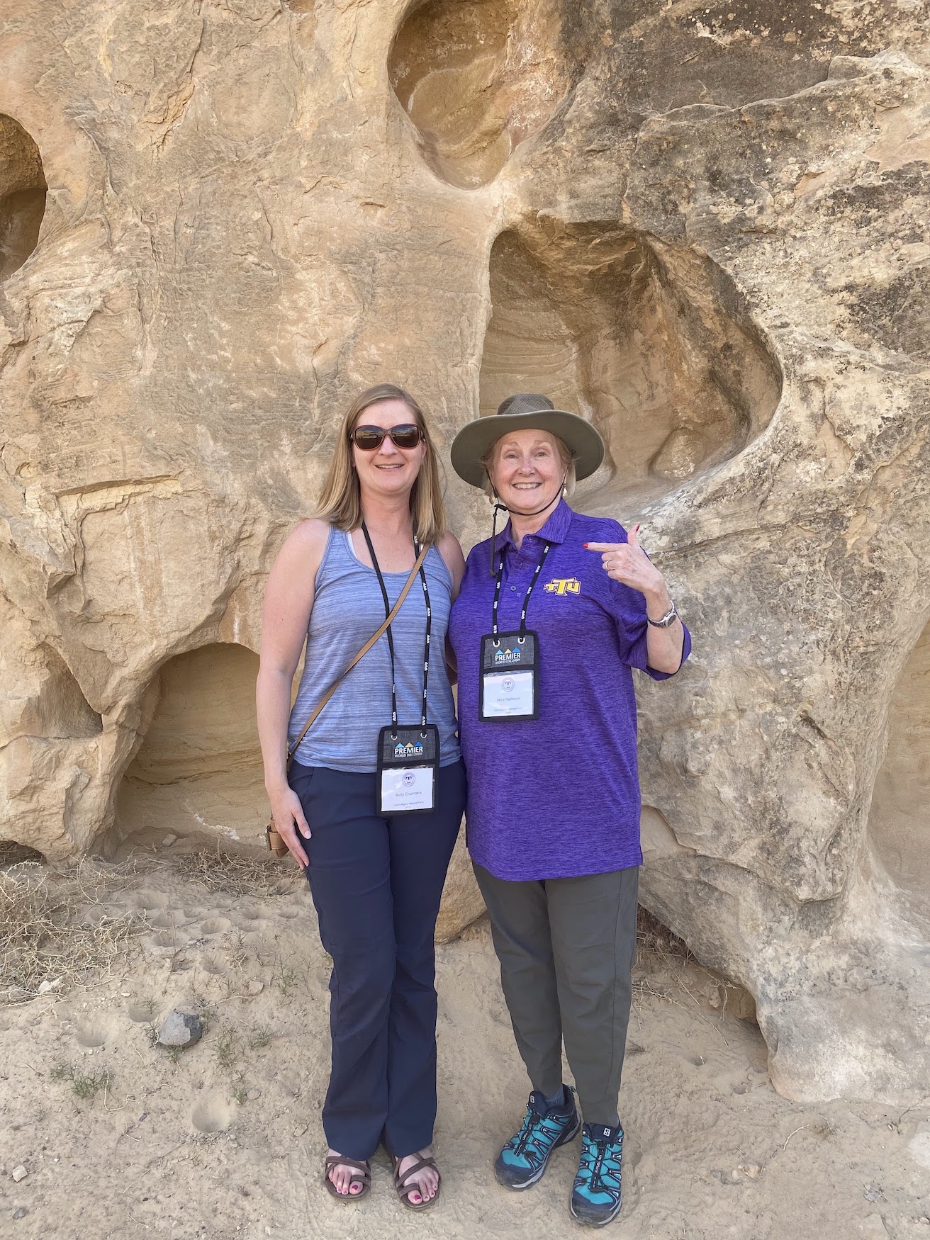 two women smile in front of pitted sandstone