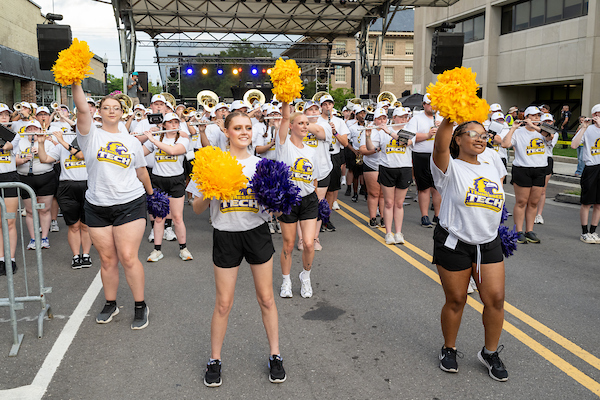 A groupd of cheer leaders in front of the stage performing cheer routines.